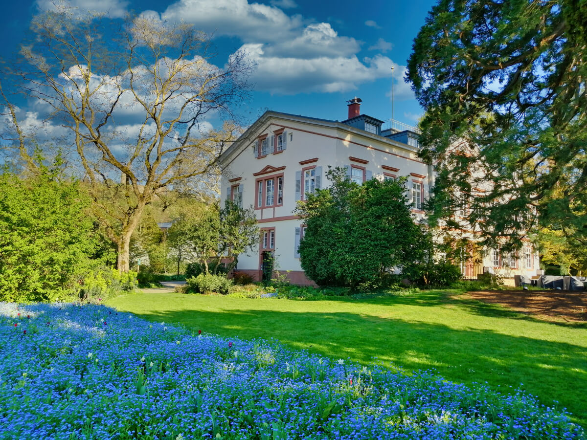 Historisches Herrenhaus im Hermannshof, umgeben von üppiger Gartenlandschaft in Weinheim.