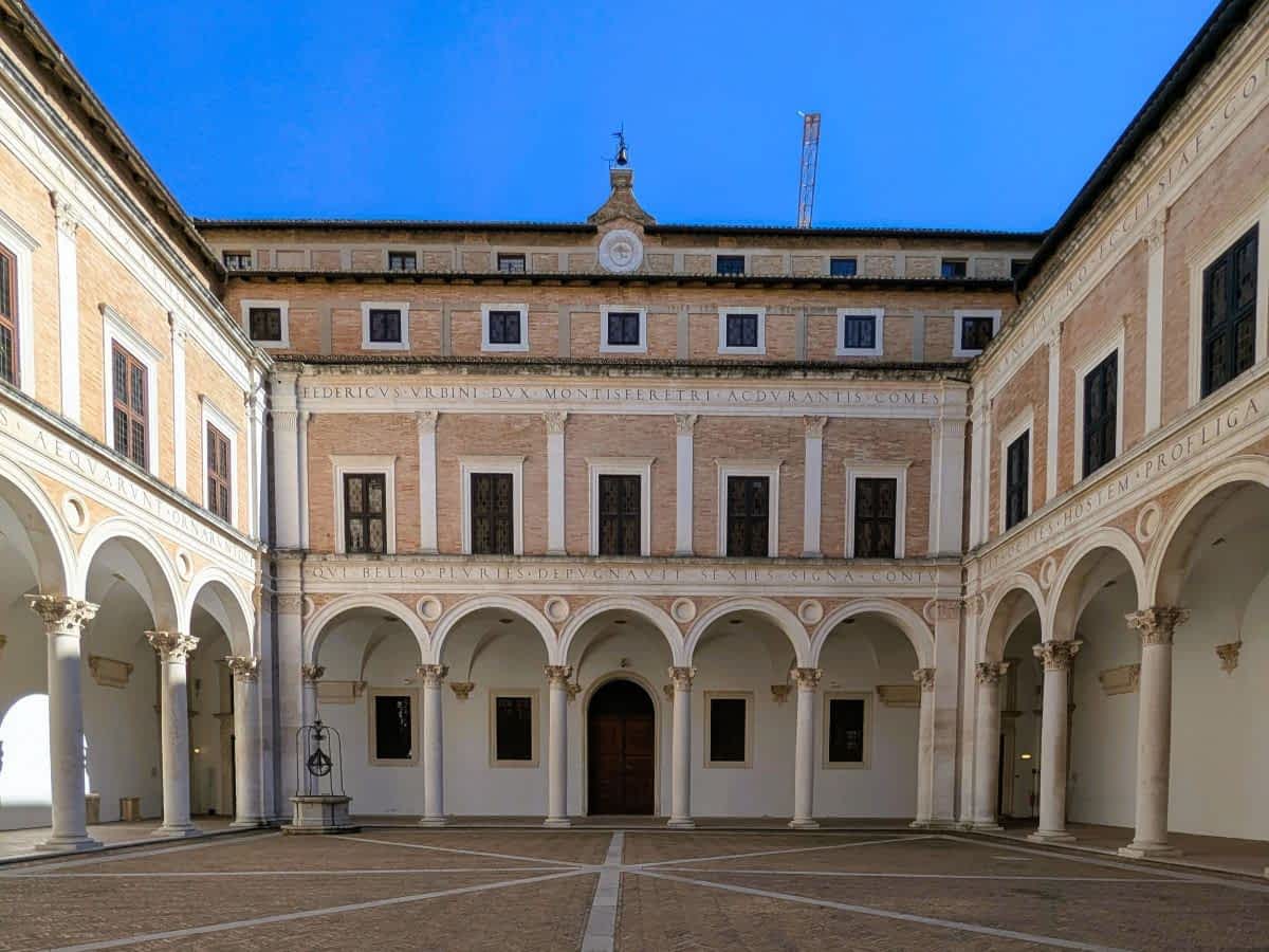 Arkadenhof der Nationalgalerie der Marken im Herzogspalast von Urbino mit Säulen und Brunnen.