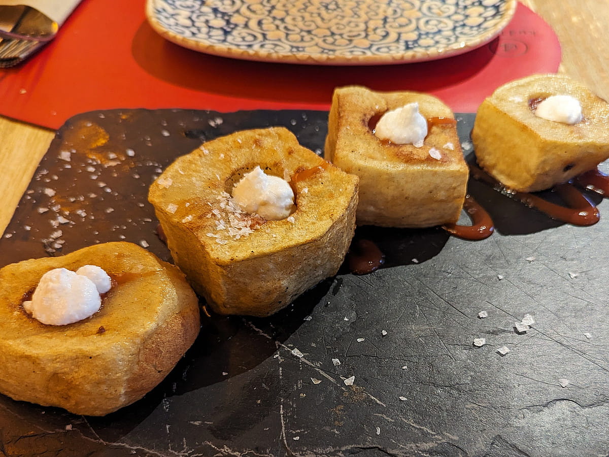 Teller mit modern interpretierten Patatas Bravas, serviert auf dunklem Stein