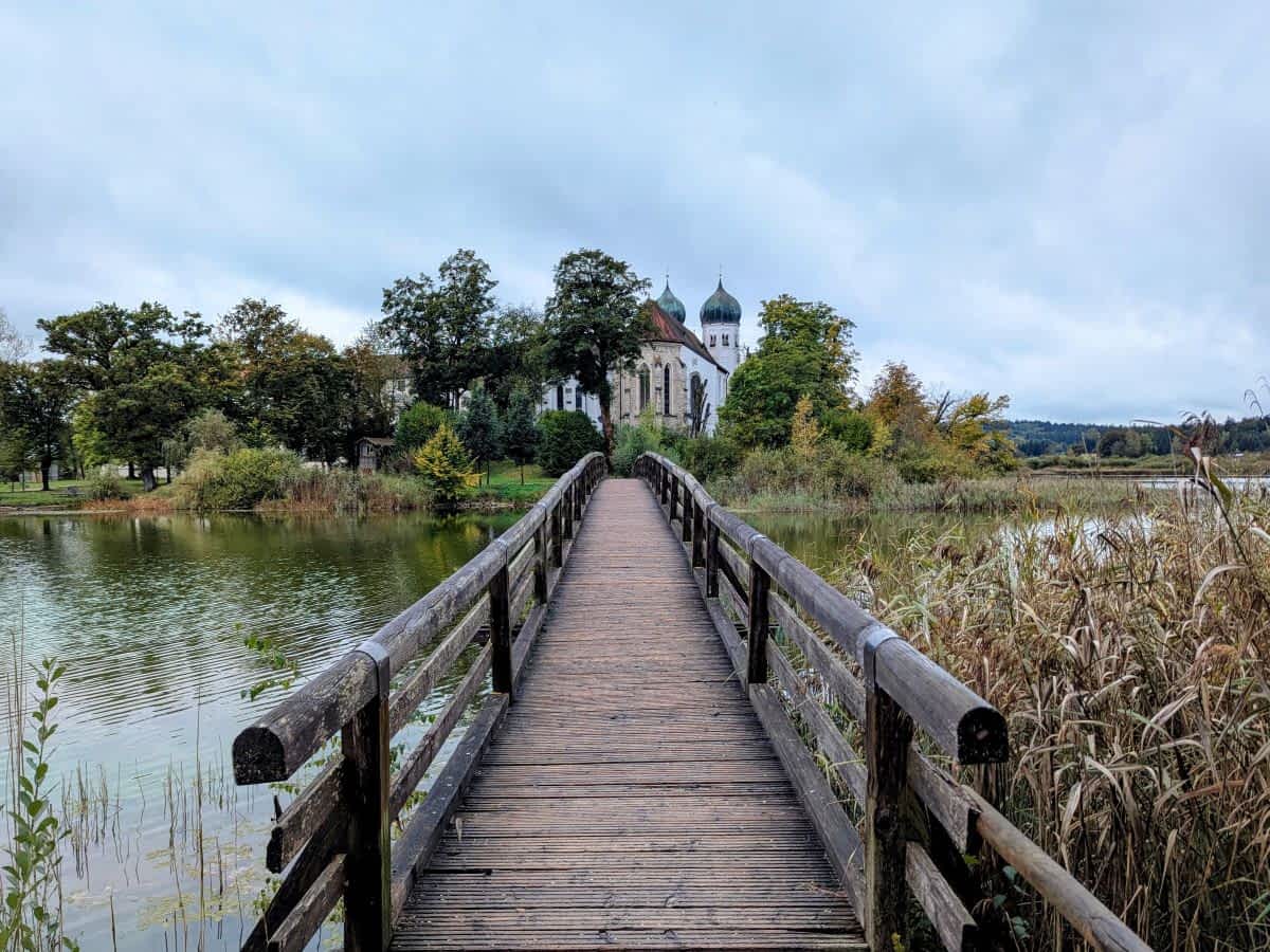 Eine Holzbrücke führt die kleine Halbinsel, auf der das Kloster Seeon mit seinen markanten Zwiebeltürmen steht.